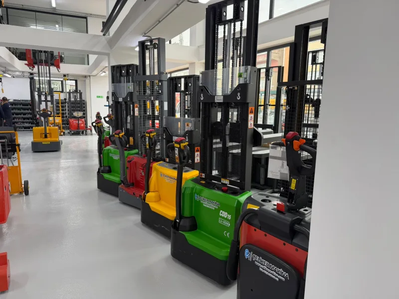 Green, red and yellow electric stackers lined up in the showroom, with a lithium-ion CDD15 model in front